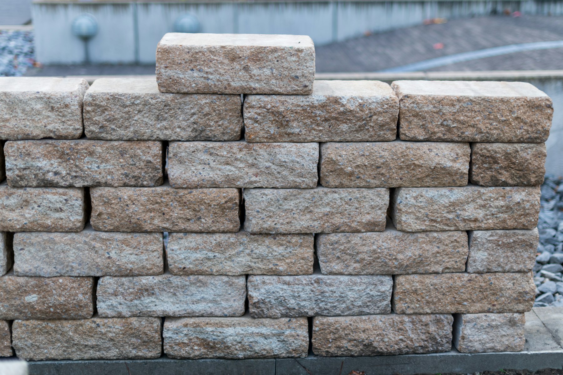 Stacked-stone retaining wall holding a graded slope
